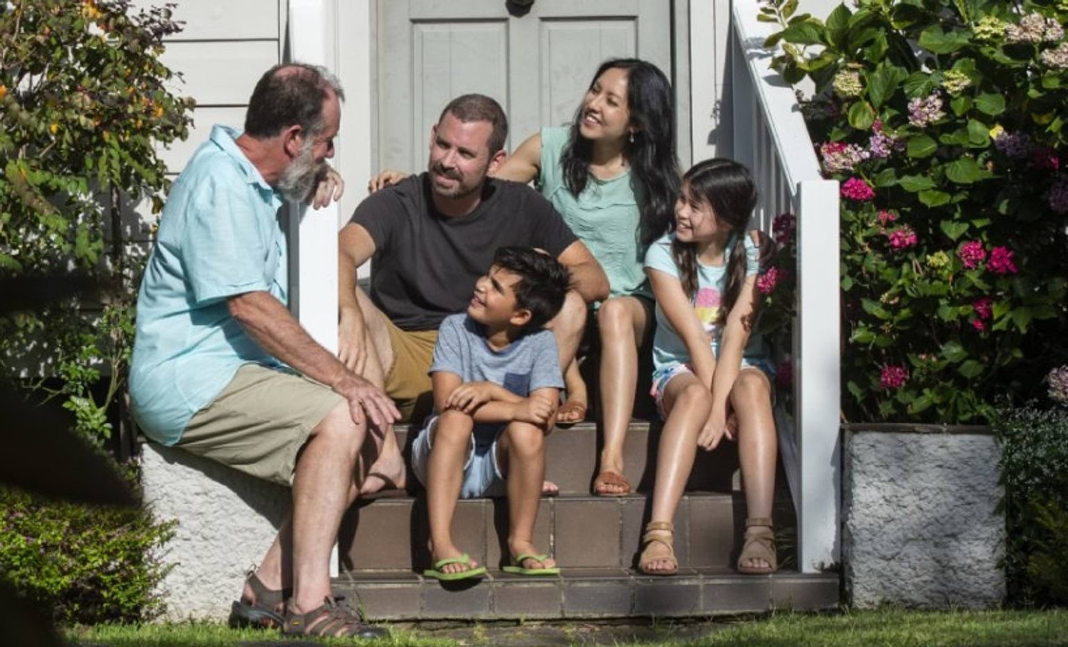 family of five sitting on steps outside a house