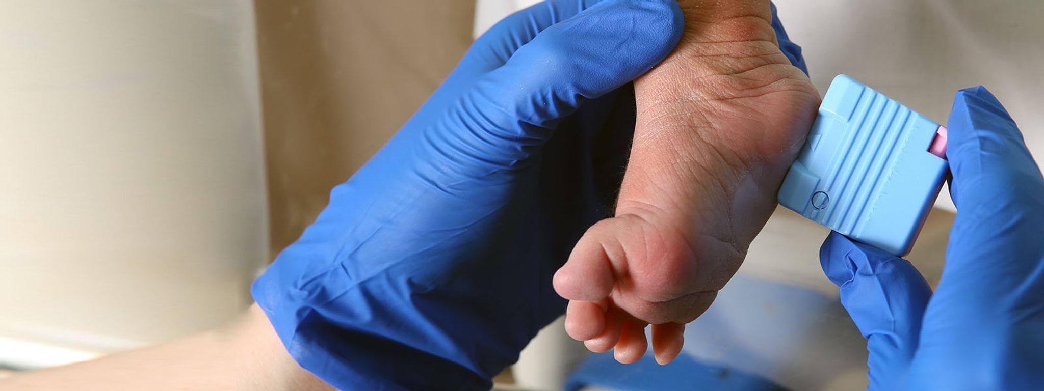 baby foot being held by blue gloved hands