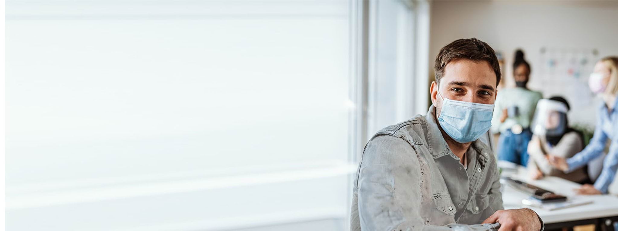 man in mask with team behind him at desk