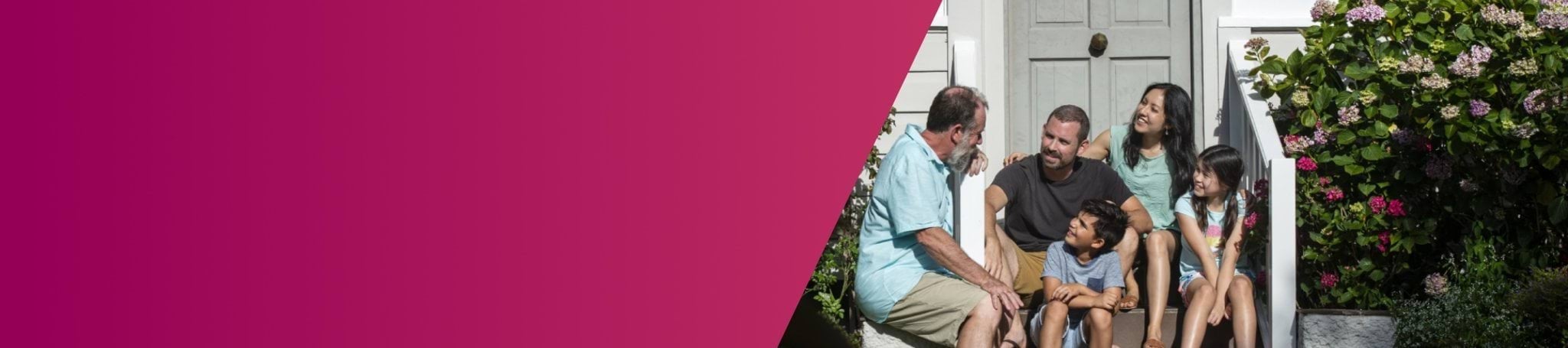 family of five sitting outside a house on a step next to a garden