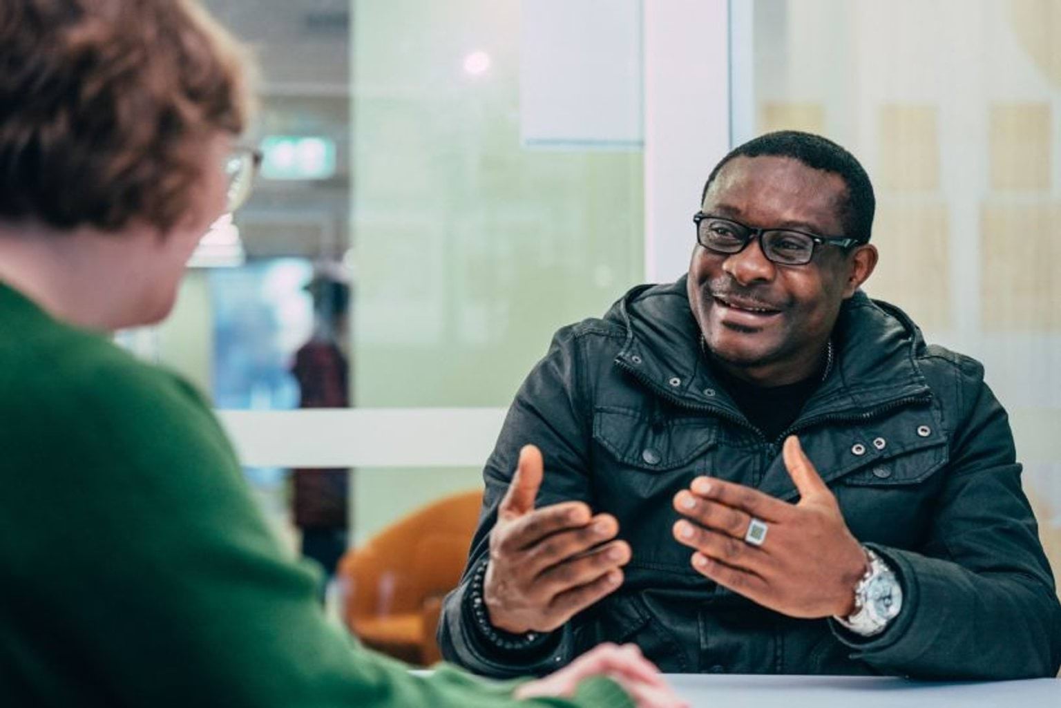 Two people in conversation at a table, at a Distress Support Service.
