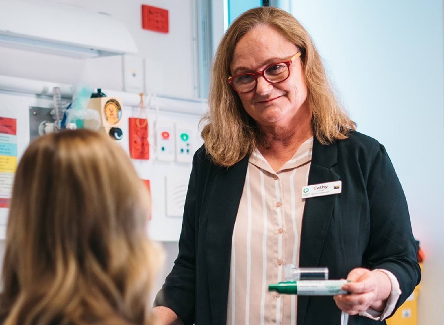 A nurse consults with a patient. She is holding a green whistle pain relief.