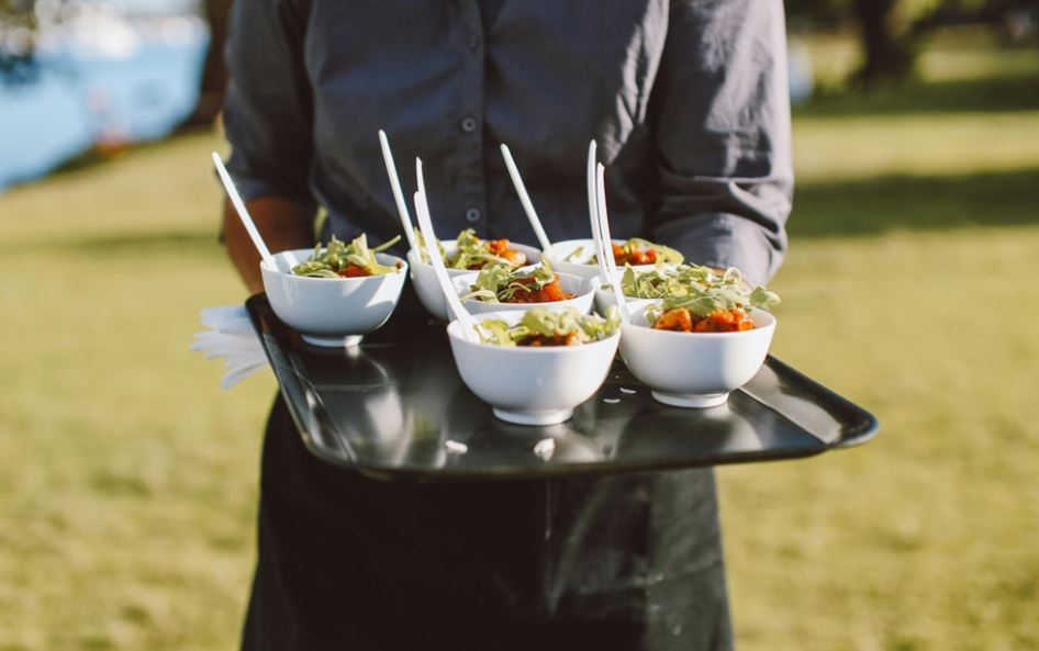 A server holding a tray of white bowls with food in them.